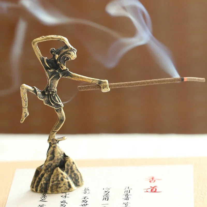 Bronze incense holder shaped like a person with a bow and arrow, emitting smoke on a wooden surface.