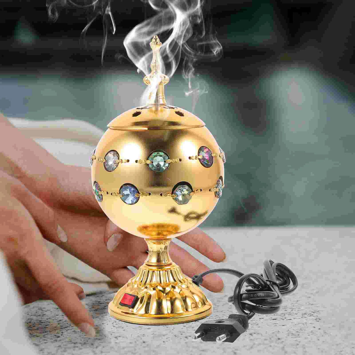 Decorative gold incense burner with crystals on a blurred background