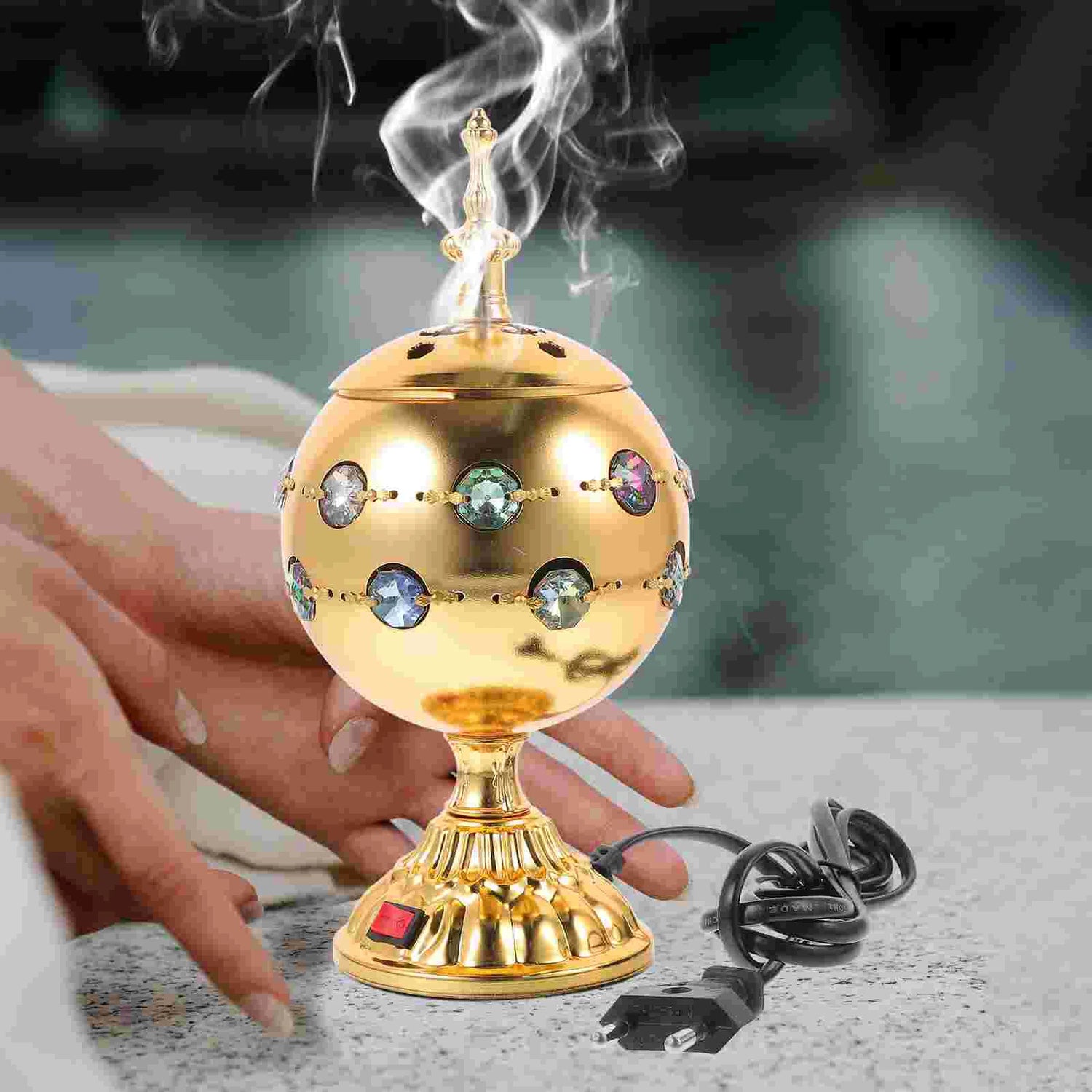 Decorative gold incense burner with crystals on a blurred background
