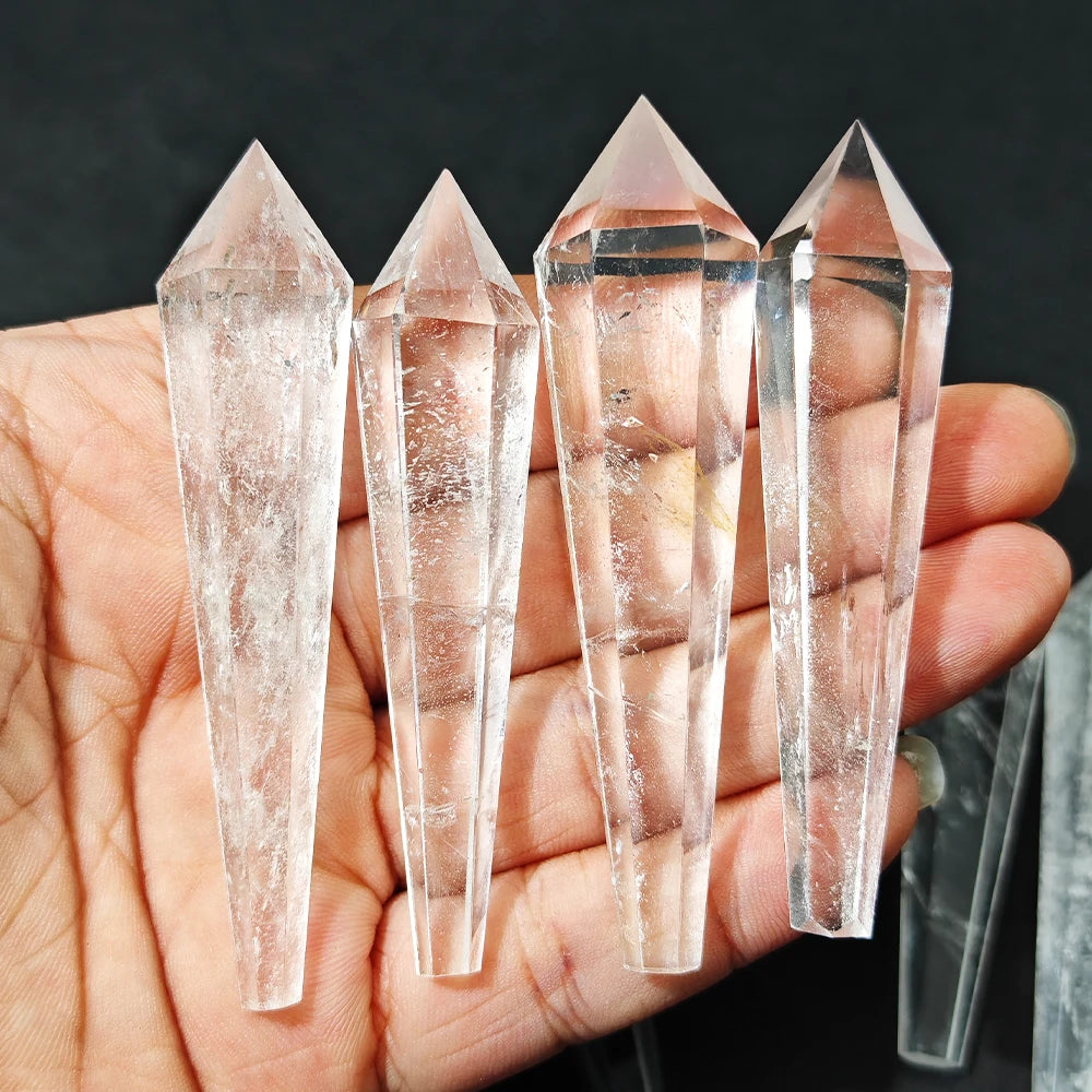 Four crystal points held in a hand against a dark background