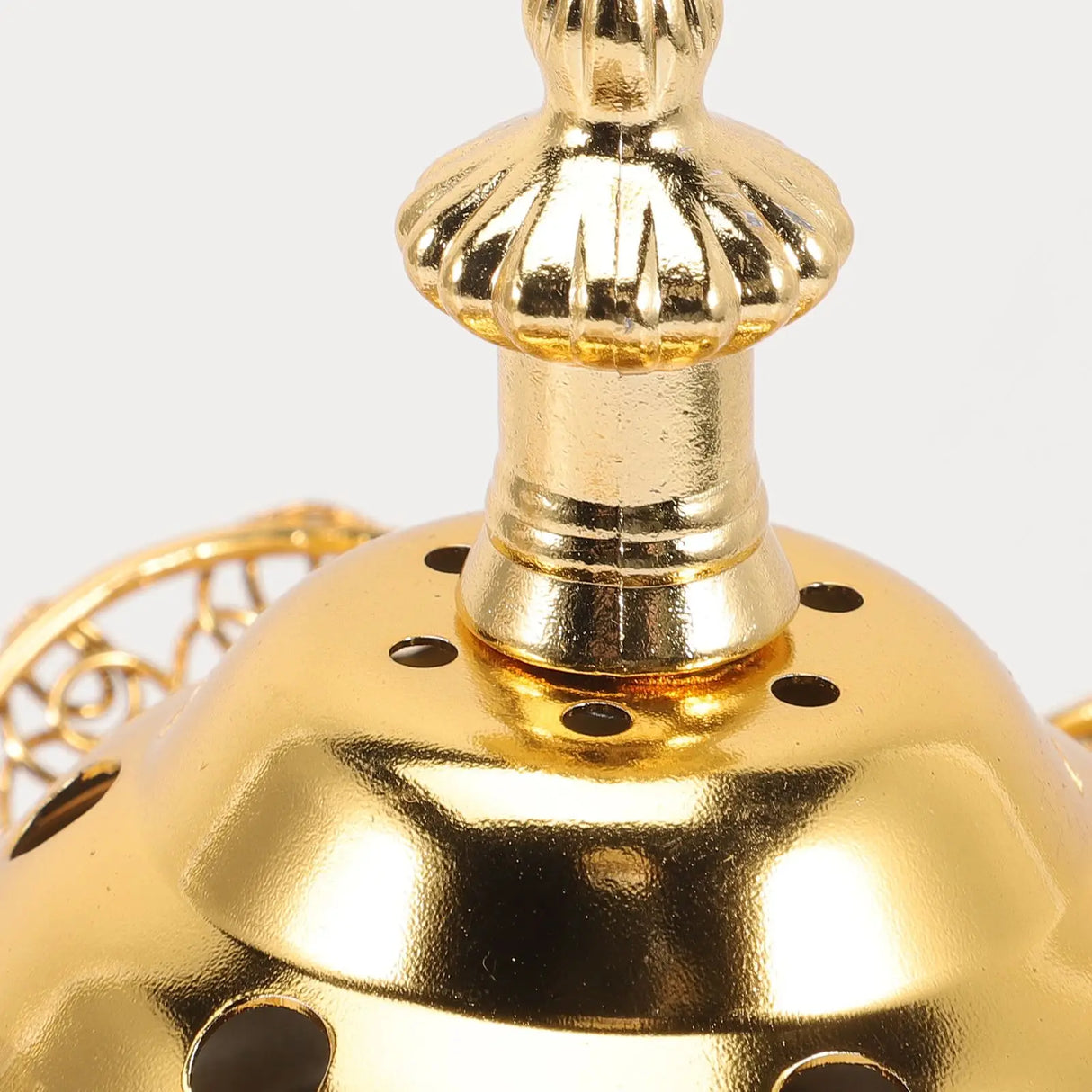 Close-up of a gold-colored decorative object with intricate design on a white background