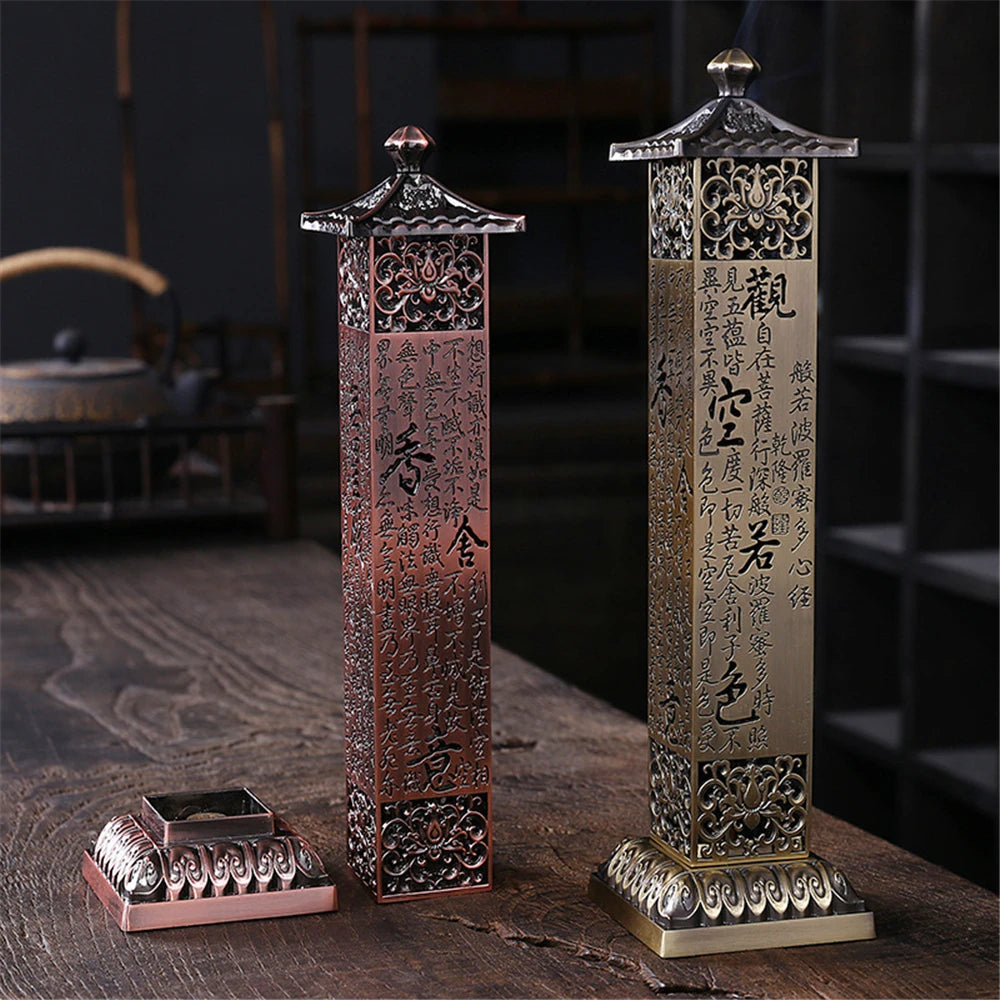 Two ornate metal pillars with intricate designs and text on a wooden surface.