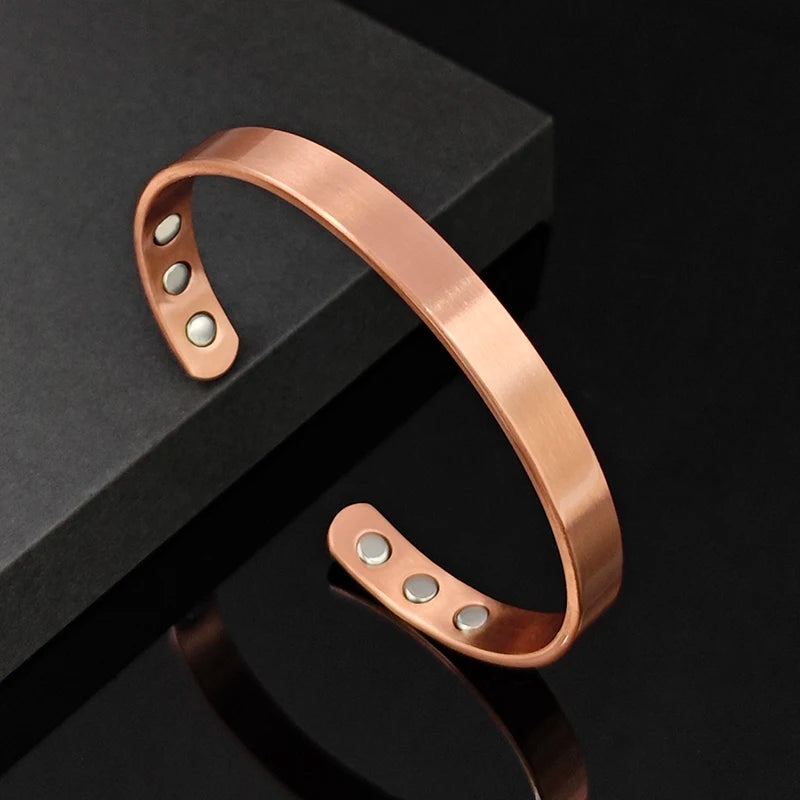 Rose gold bracelet with metallic stones on a black surface