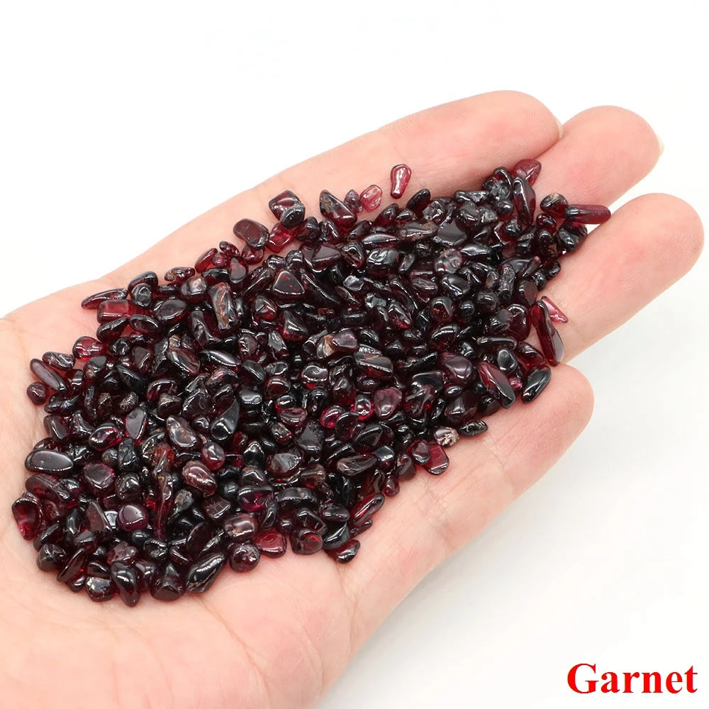 Hand holding garnet stones with 'Garnet' text on a white background