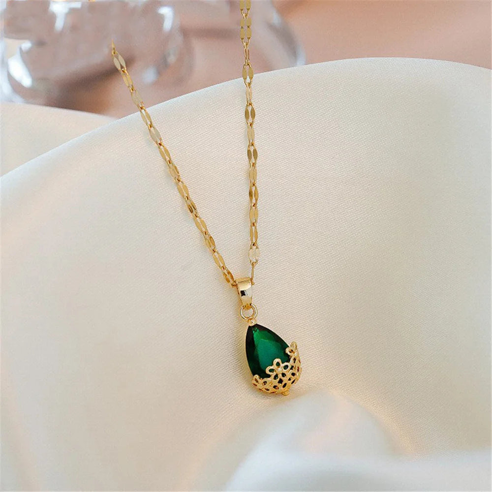 Gold necklace with a green pendant on a white surface