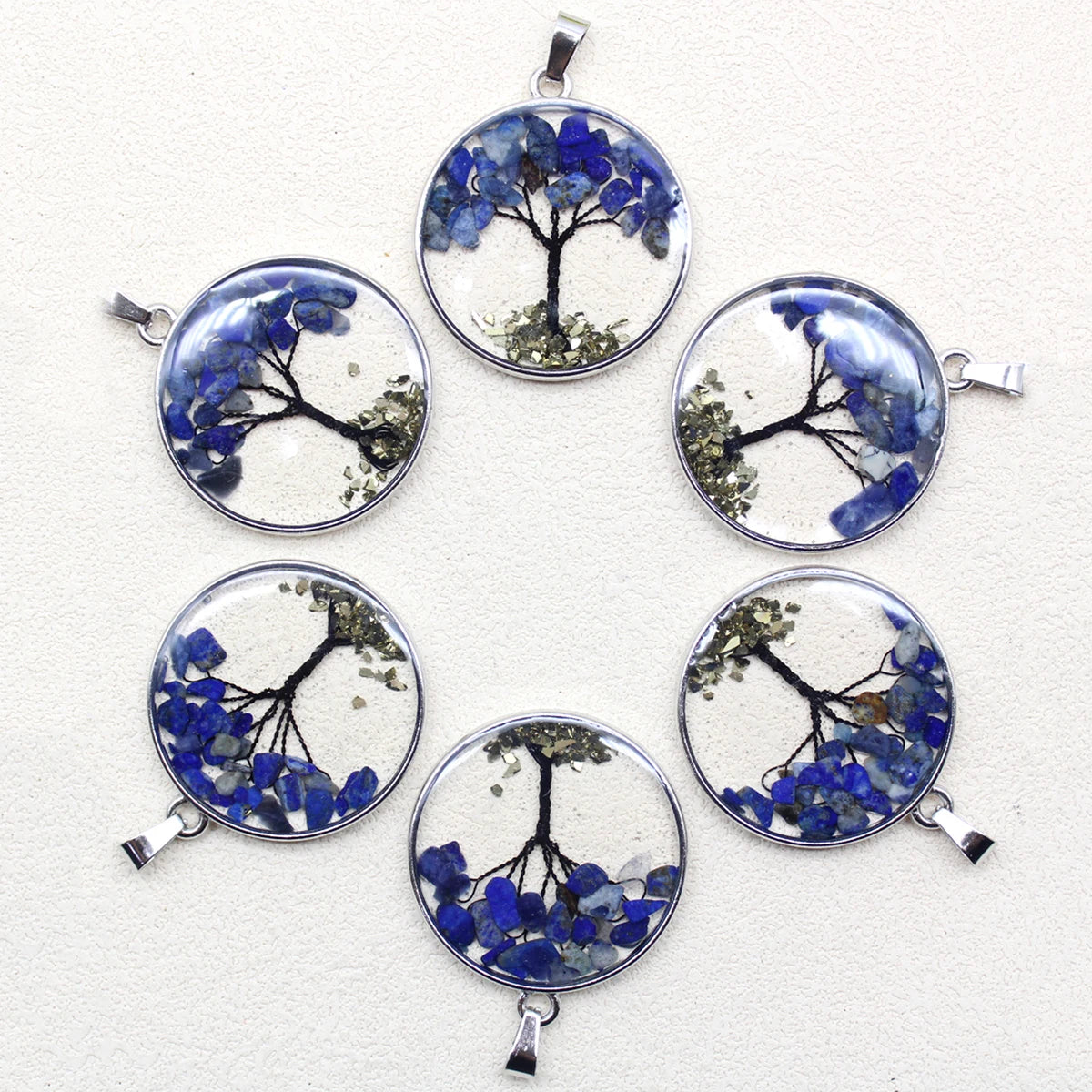 Set of six circular pendants with tree designs and blue flowers on a white background