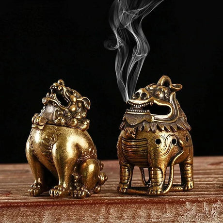 Two ornate brass incense burners on a wooden surface with a dark background