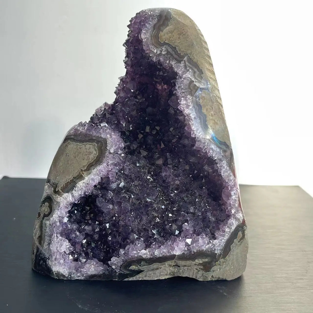 Amethyst geode on a reflective surface with a neutral background