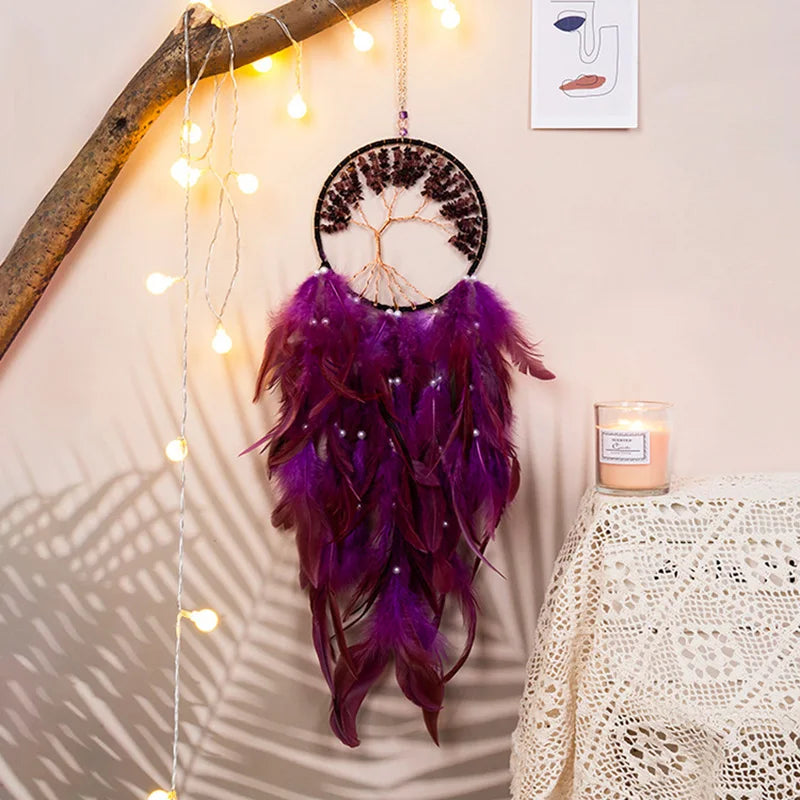 Purple feathered dreamcatcher hanging on a wall with string lights and a candle.