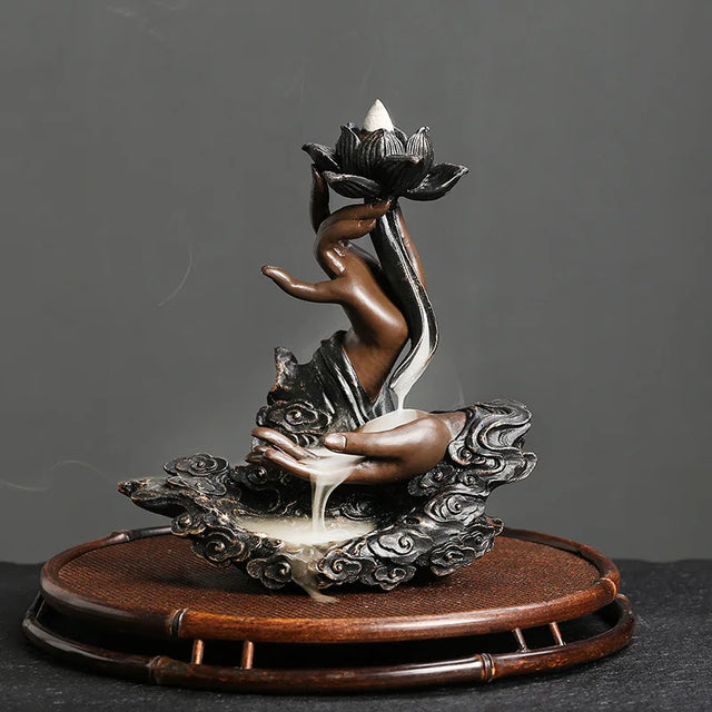 Decorative incense burner with a lotus flower and hands on a dark background