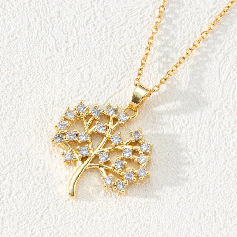 Gold necklace with a leaf-shaped pendant on a light background