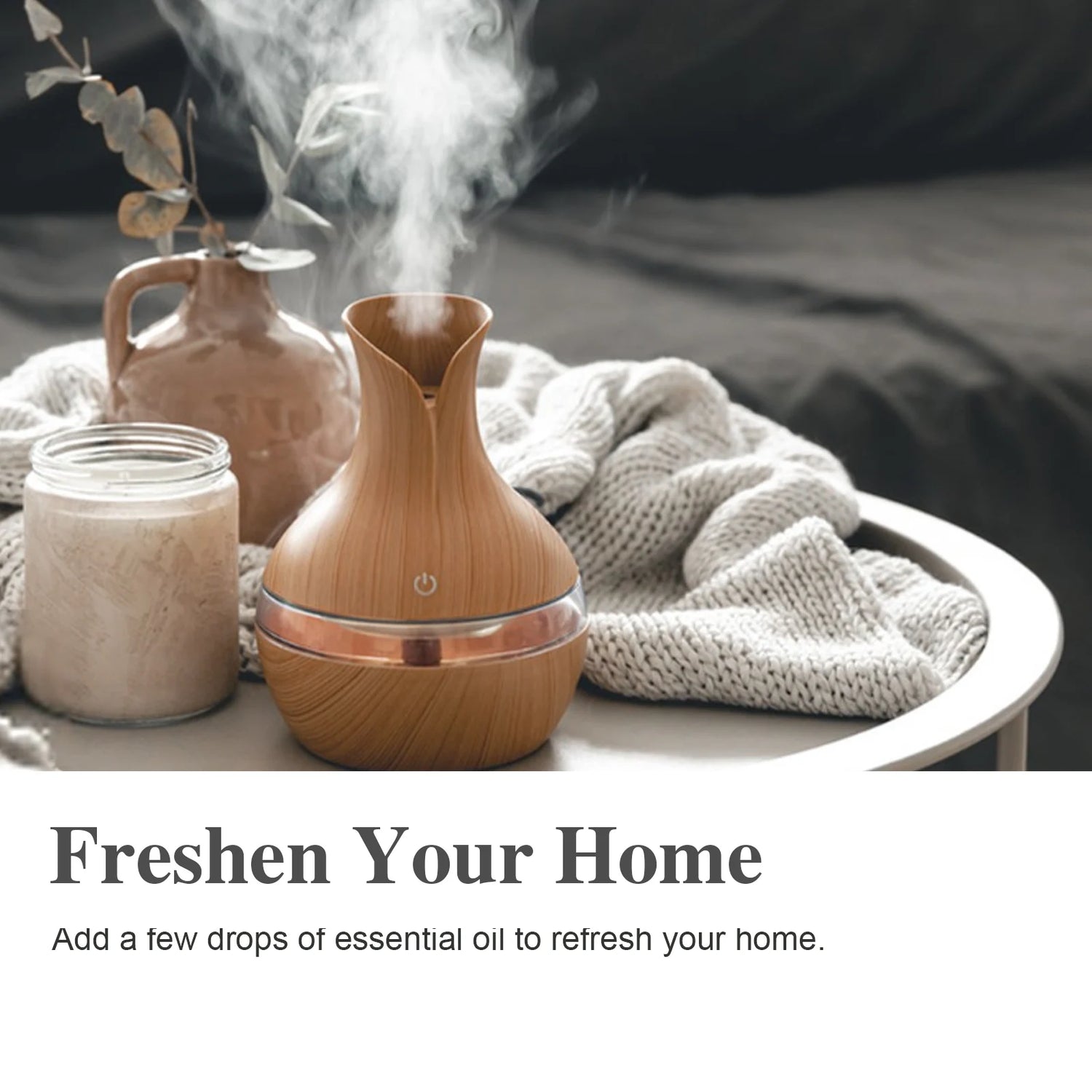 Wooden diffuser emitting steam with a jar of liquid and decorative vase on a soft surface.