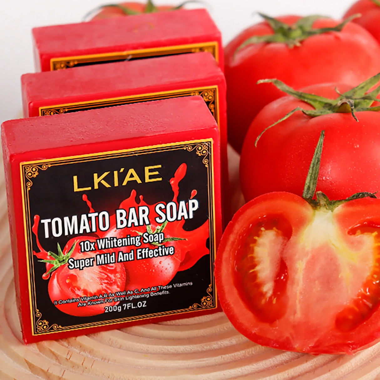 Red soap bars with tomato design and packaging, surrounded by whole and sliced tomatoes on a wooden surface.