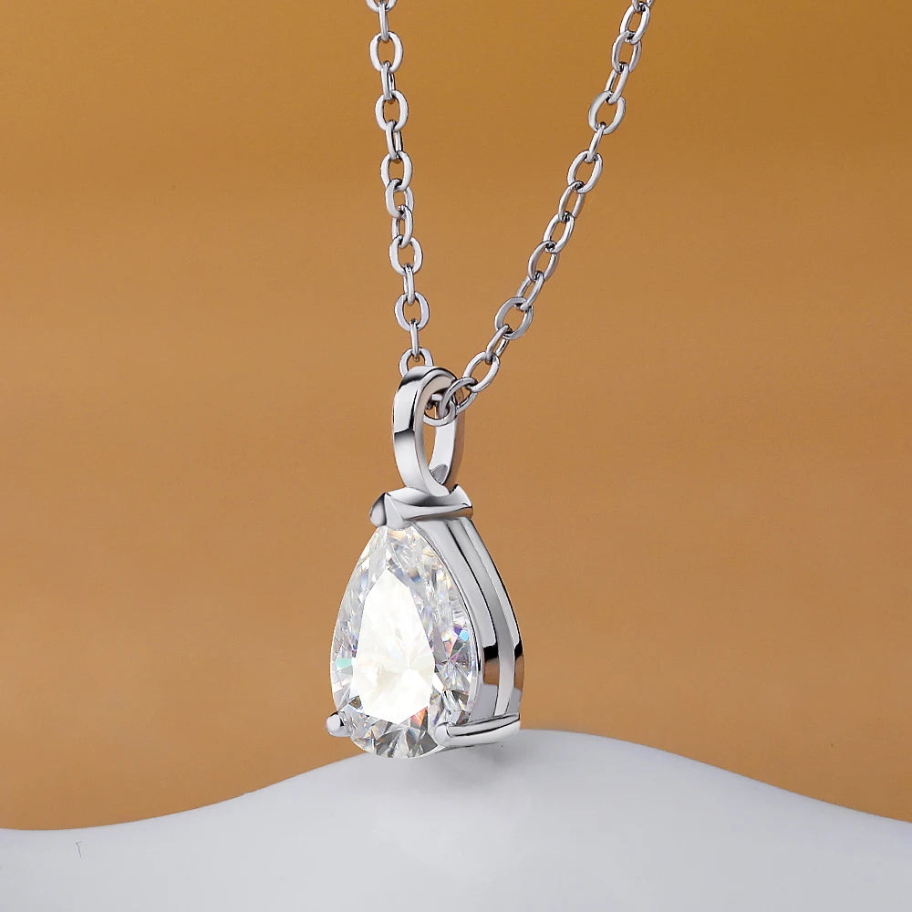 Silver necklace with a teardrop-shaped diamond pendant on a beige background