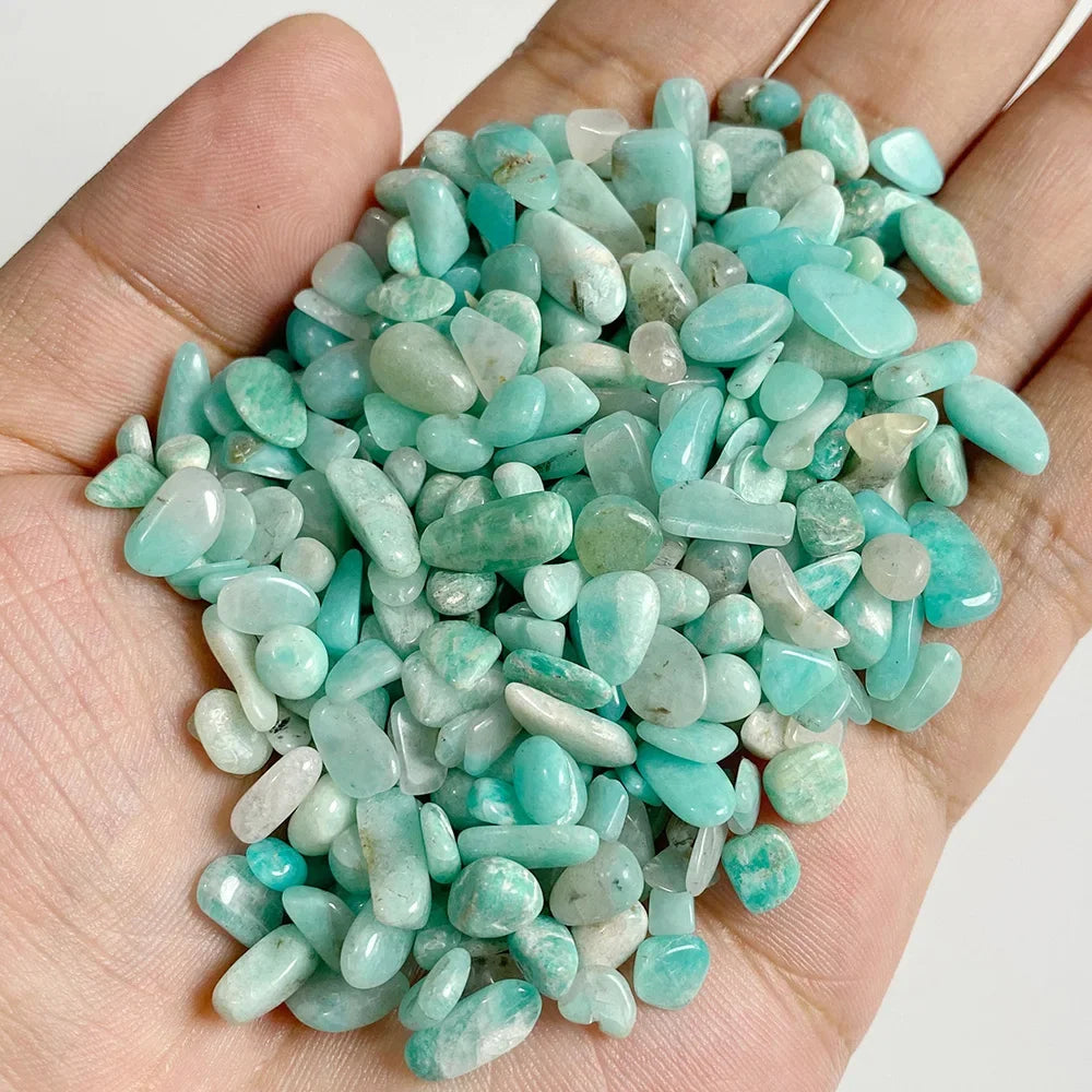 Hand holding a pile of turquoise stones against a white background