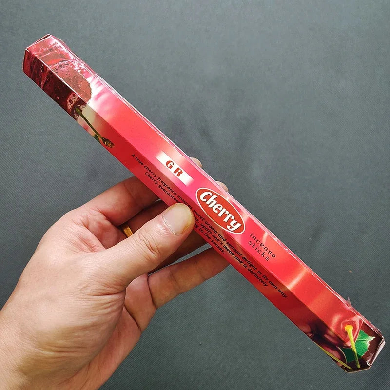 Hand holding a red Cherty product packaging against a gray background
