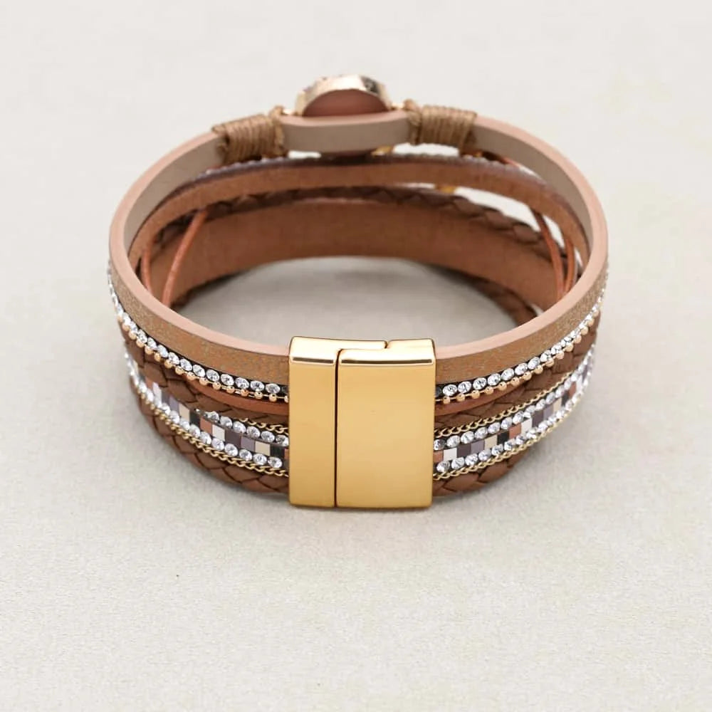 Brown leather bracelet with gold clasp on a light gray background