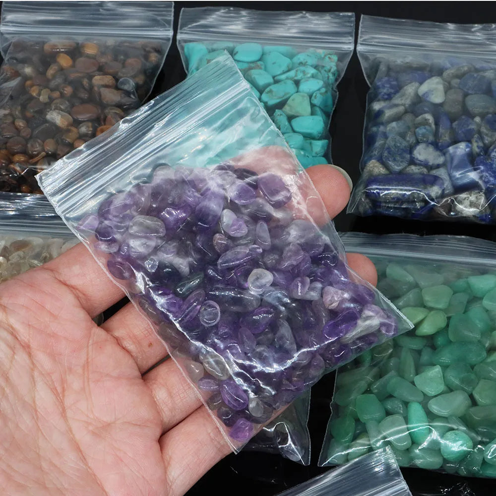 Hand holding a bag of purple stones with other colored stones in the background
