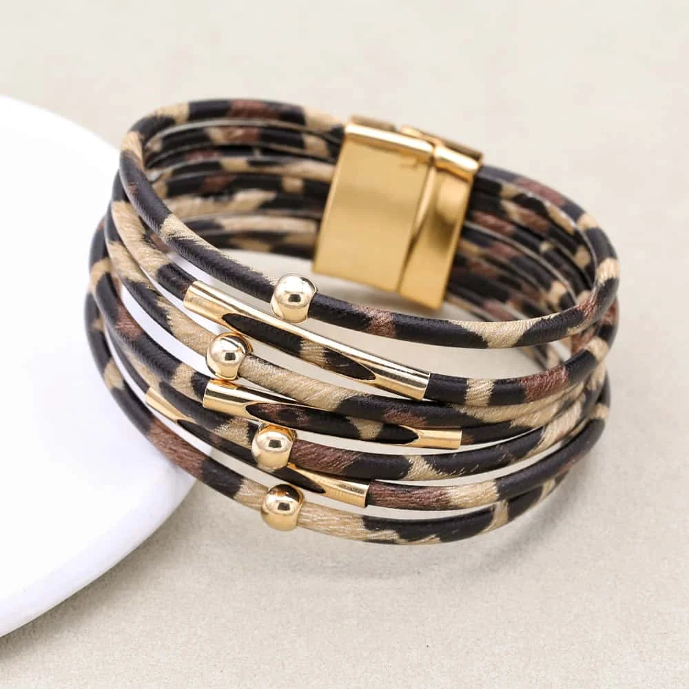 Leopard print bracelet with gold accents on a beige background
