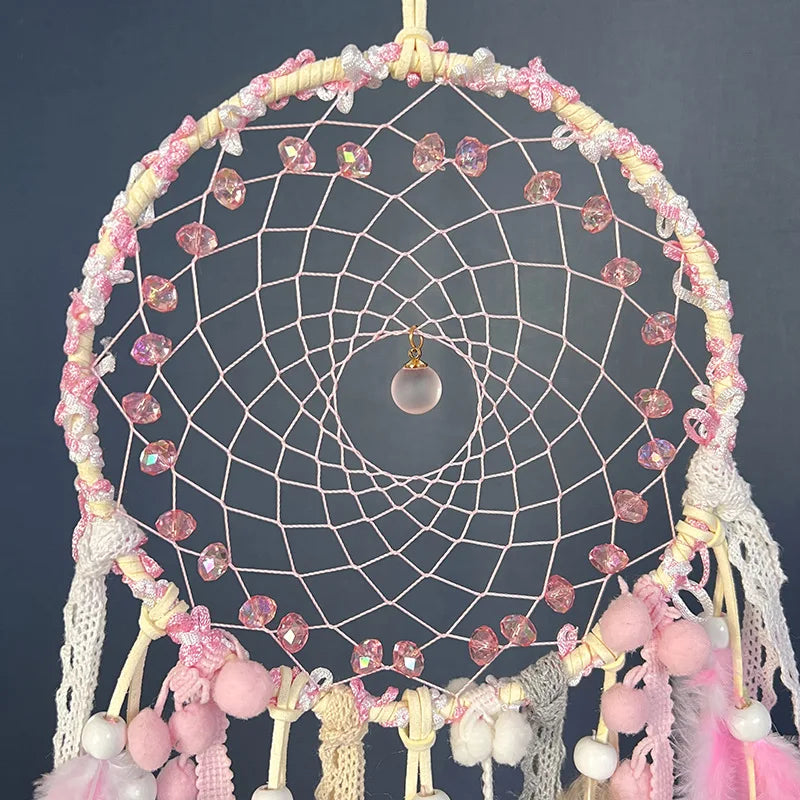 Decorative dreamcatcher with pink and white elements on a dark background