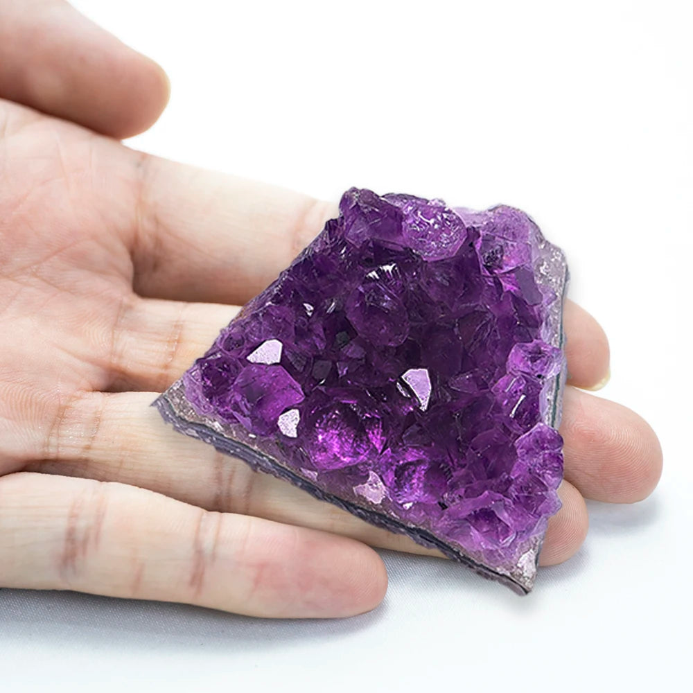 Hand holding a purple crystal rock on a white background