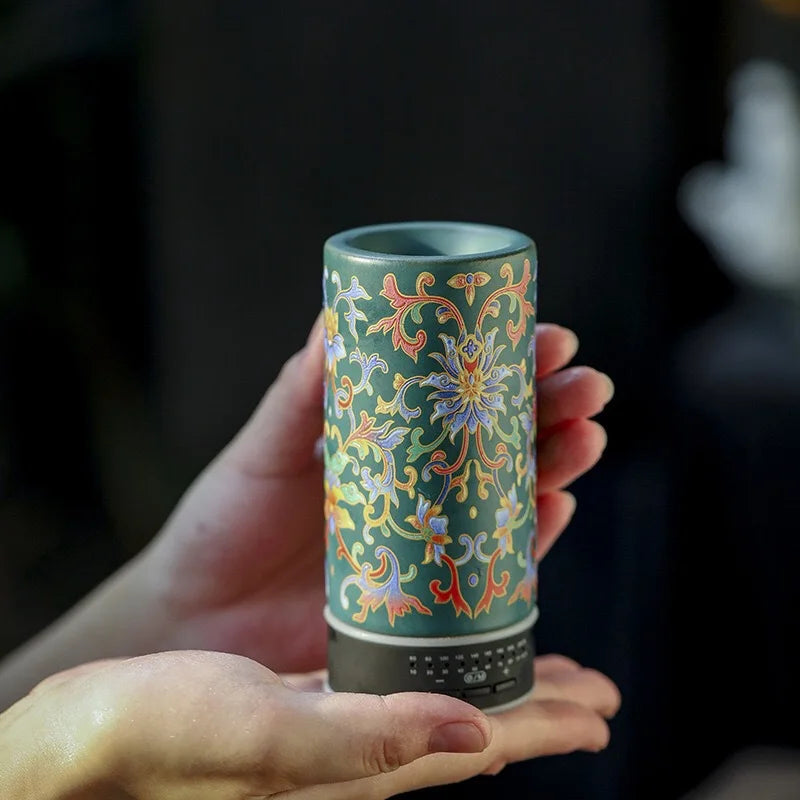 Hand holding a cylindrical ceramic container with intricate floral patterns against a dark background