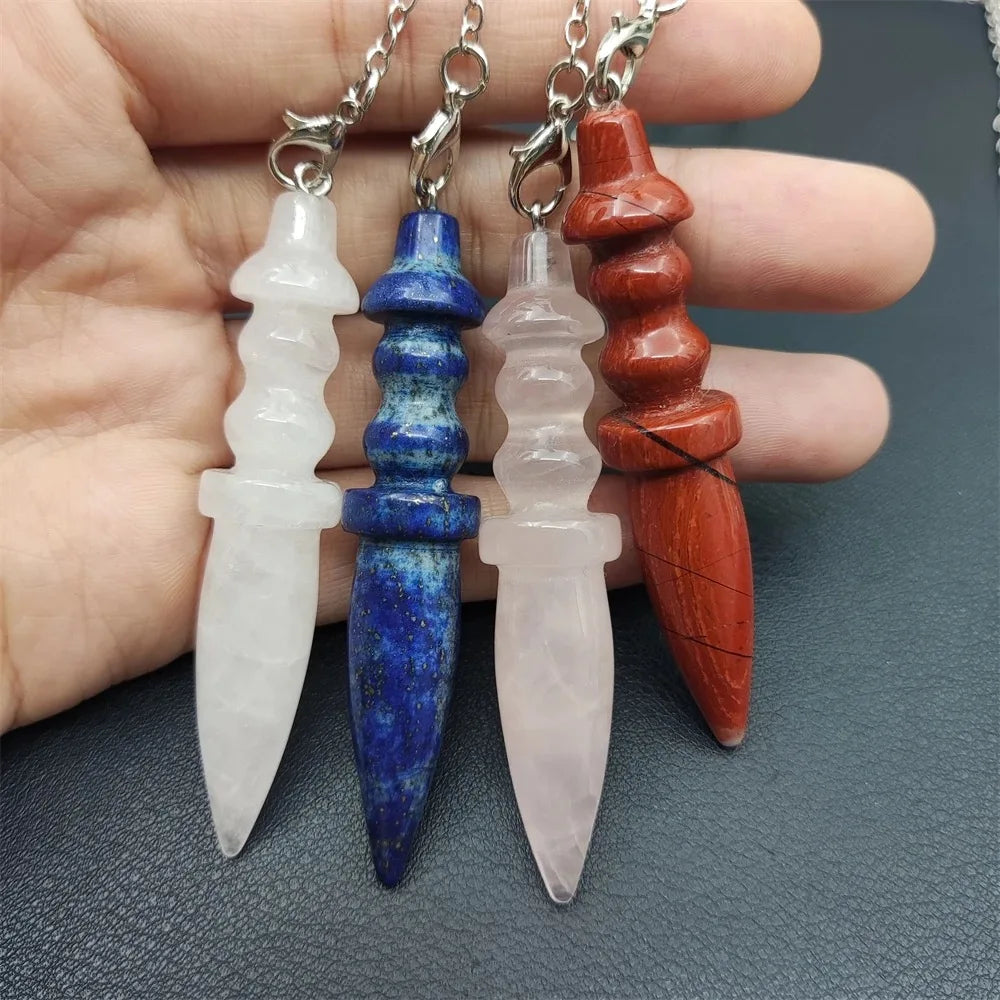 Four crystalpendants of different colors held by a hand on a gray background