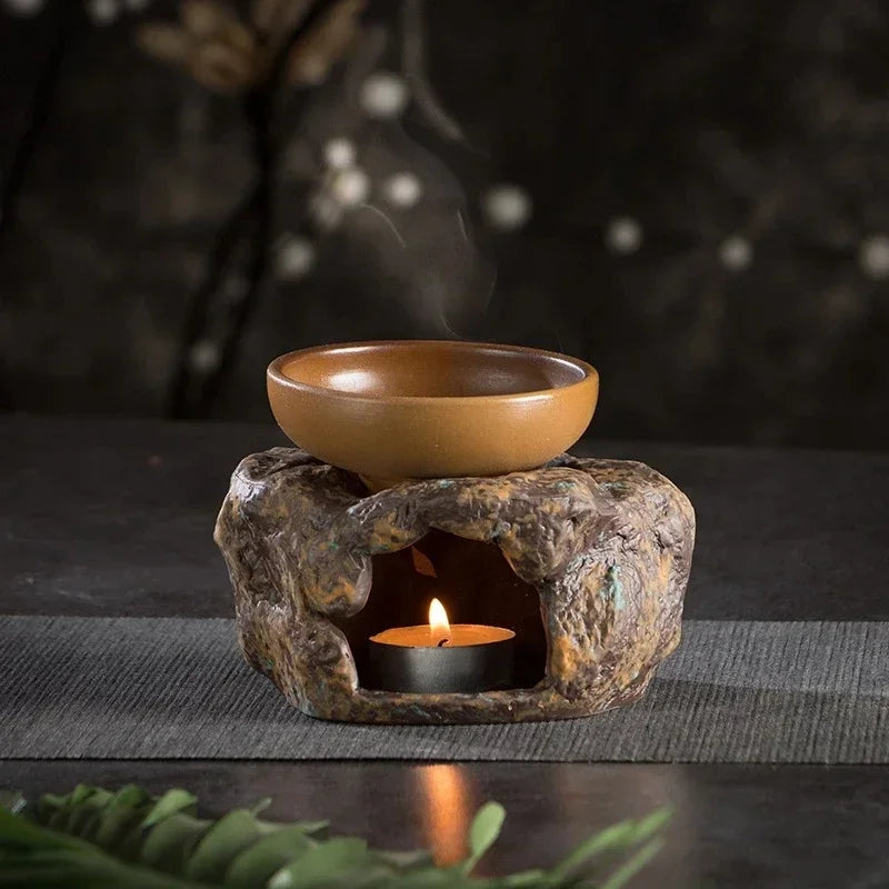 Ceramic oil burner with a lit candle on a dark surface