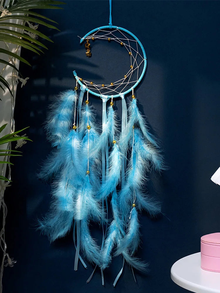 Blue dreamcatcher with feathers against a dark blue wall