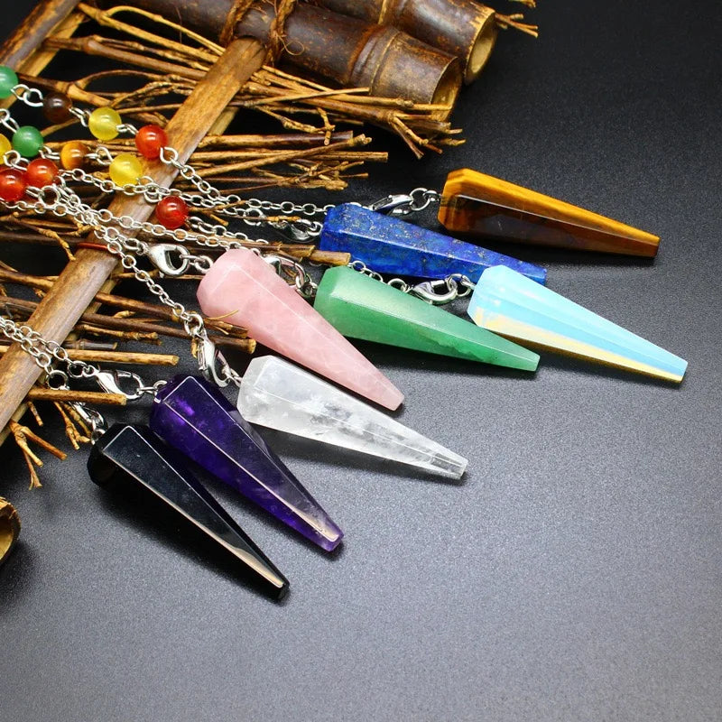 Colorful crystal pendulums on a dark surface with wooden elements.