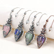 Five decorative pendants with colorful gemstones on a white surface