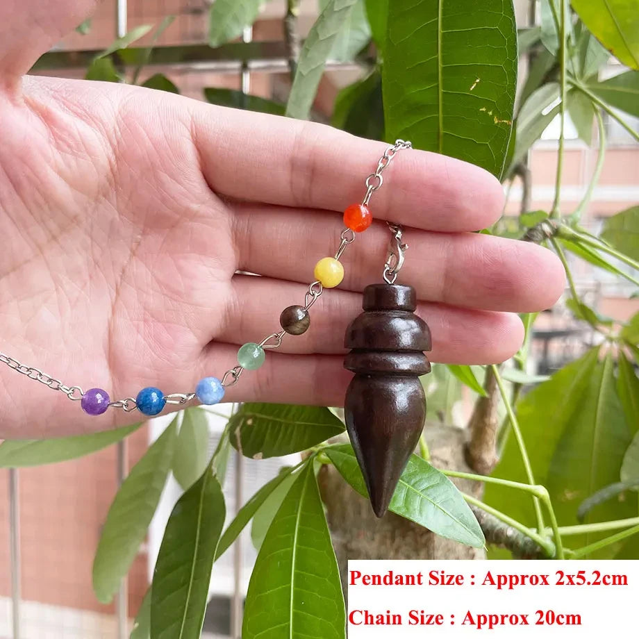 Hand holding a necklace with a wooden pendant and colorful beads against a leafy background
