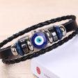 Black braided leather bracelet with blue evil eye charm on a beige background
