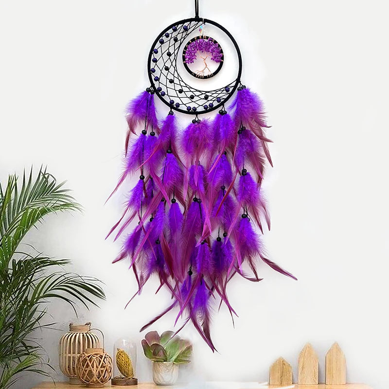 Purple feather dreamcatcher hanging on a white wall with decorative items below.