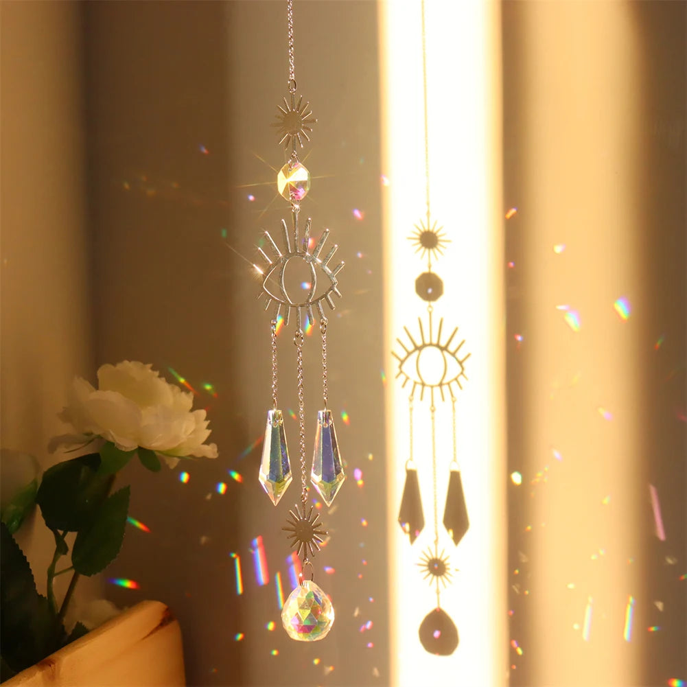 Decorative hanging crystal with sun and moon designs, casting rainbow colors on a window.