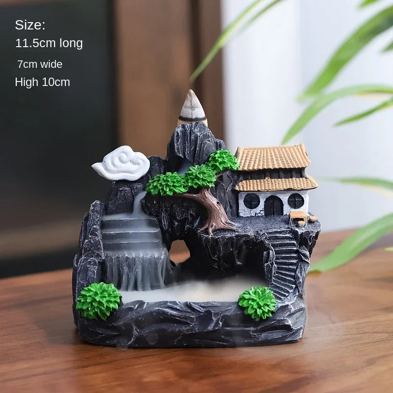 Decorative miniature landscape with a house, trees, and mist on a wooden surface.