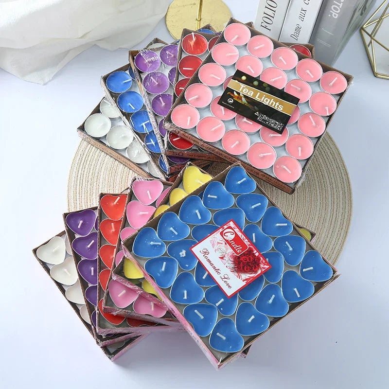Colorful tea light candles in boxes on a white surface
