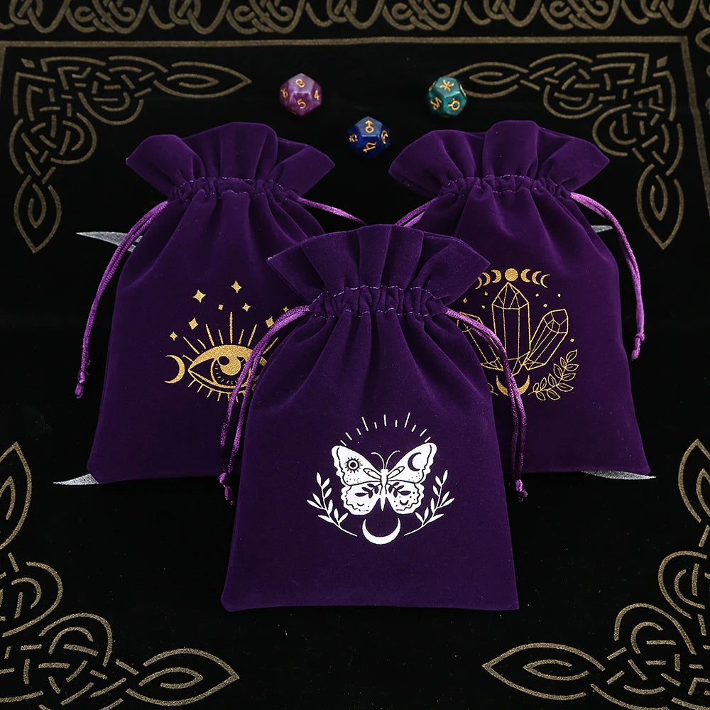 Three purple drawstring bags with mystical designs on a black background with gold patterns.