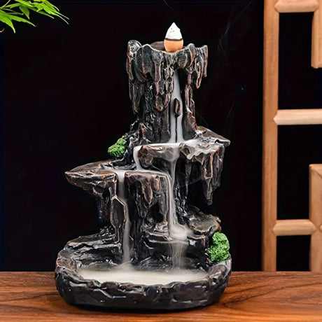 Decorative incense burner shaped like a waterfall on a wooden surface with a dark background.