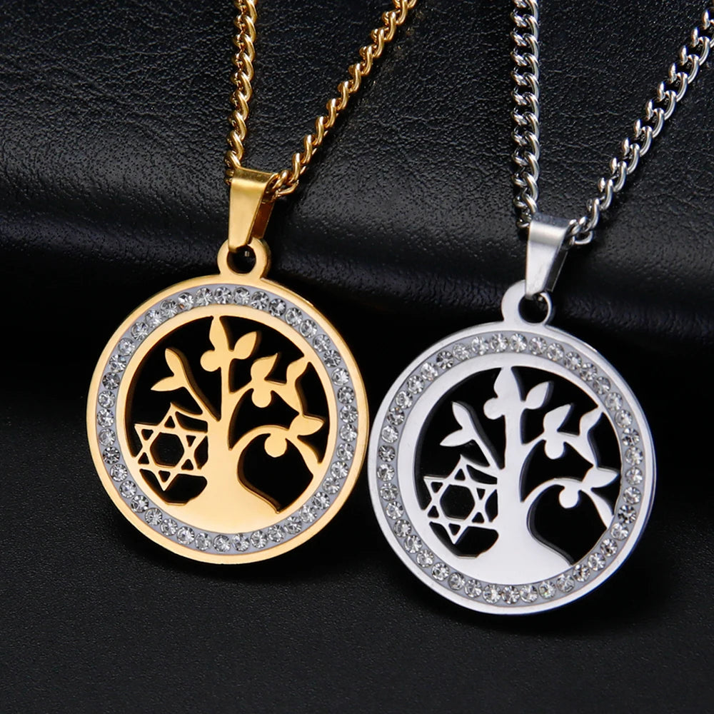 Two tree-shaped pendants, one gold and one silver, on black leather background