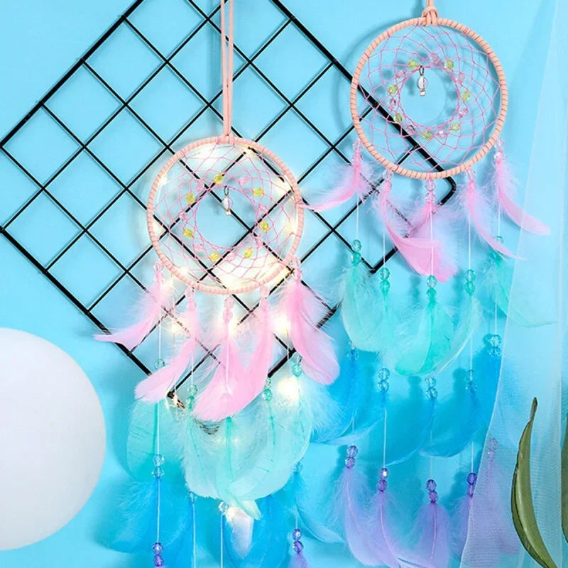 Two colorful dream catchers with pink and blue feathers on a light blue background.