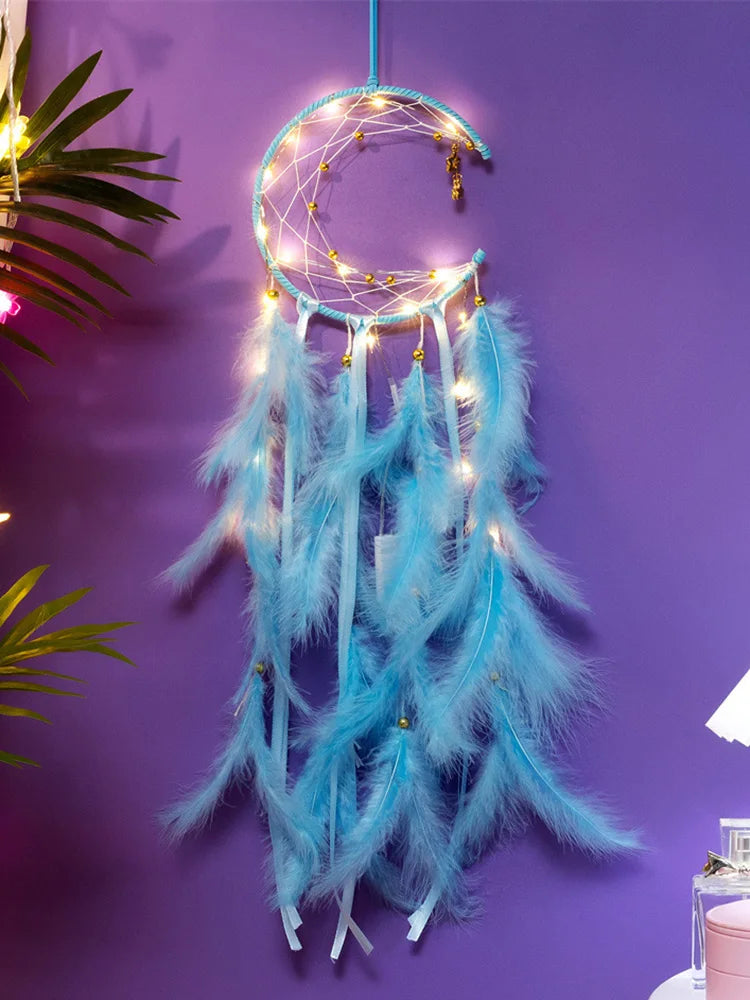 Dreamcatcher with blue feathers and string lights against a purple wall