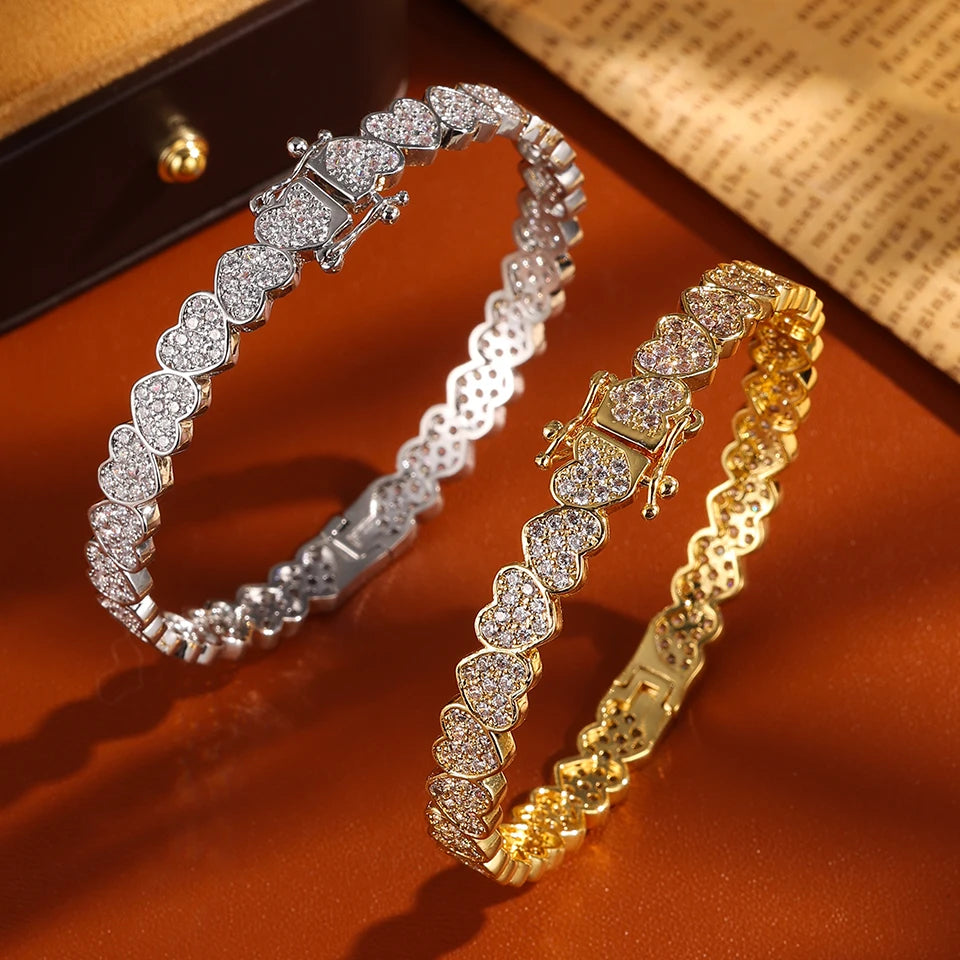 Two diamond-encrusted bracelets, one silver and one gold, on a wooden surface.