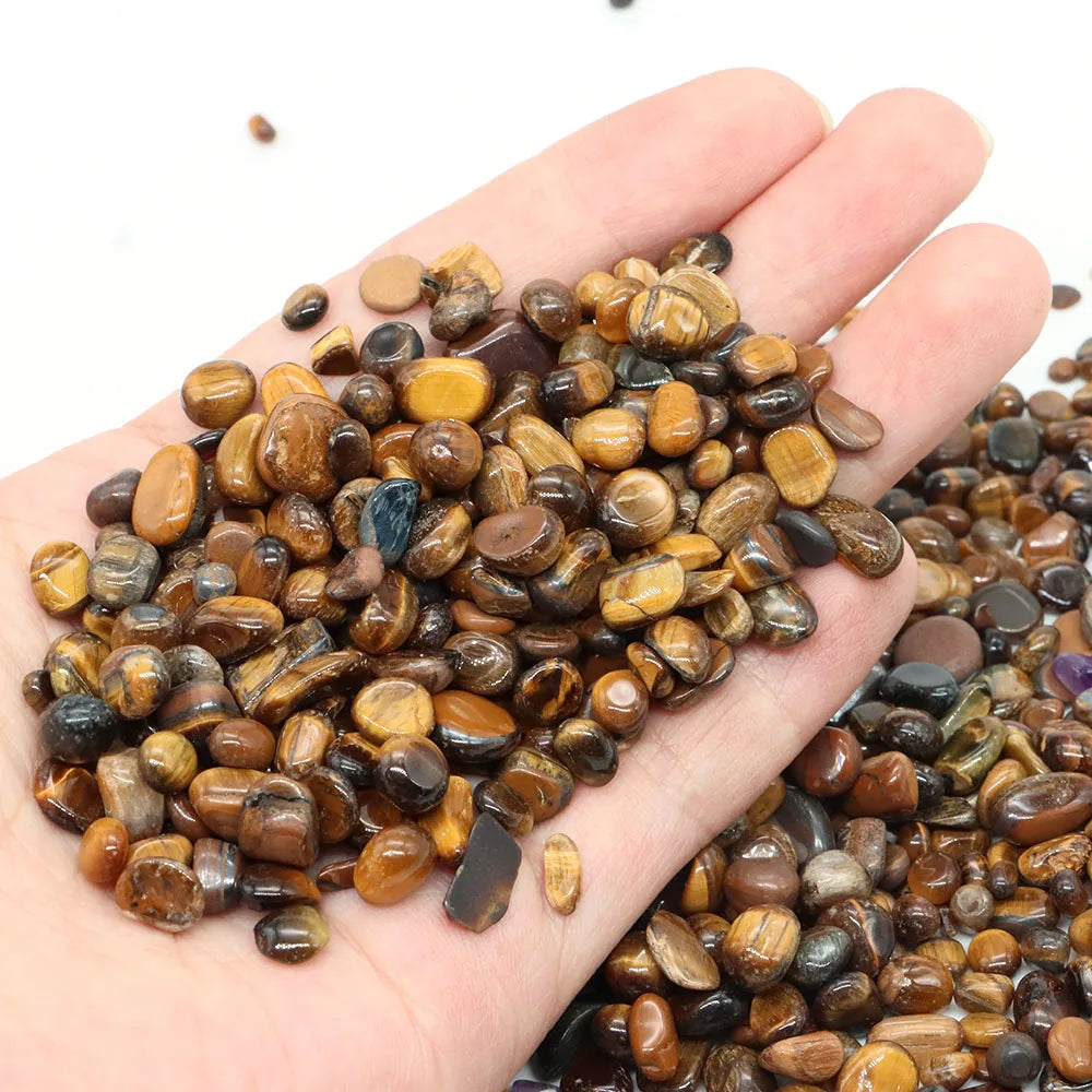 Hand holding a small pile of multicolored stones against a white background