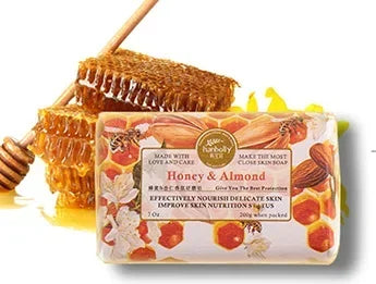 Bar of soap with honey and almond ingredients, surrounded by honeycomb and a honey dipper.