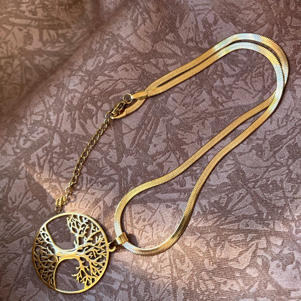 Gold necklace with a tree-of-life pendant on a textured brown fabric background