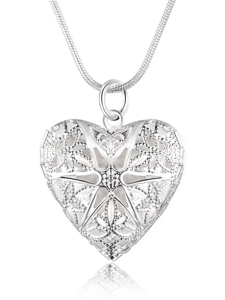 Silver heart-shaped pendant with intricate designs on a white background