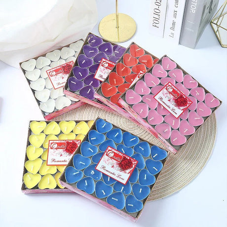 Three boxes of heart-shaped candles in various colors on a white surface.