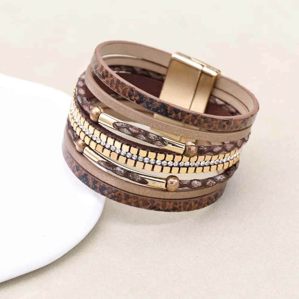 Stack of layered bracelets with gold and brown accents on a light background