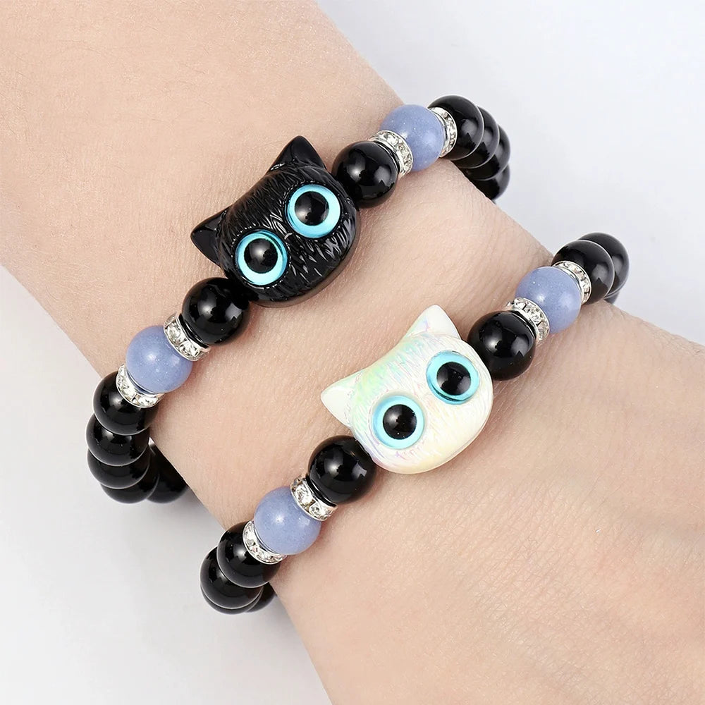 Bracelets with owl-shaped beads on a wrist against a light background